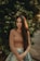 woman in brown long sleeve shirt standing near green tree during daytime