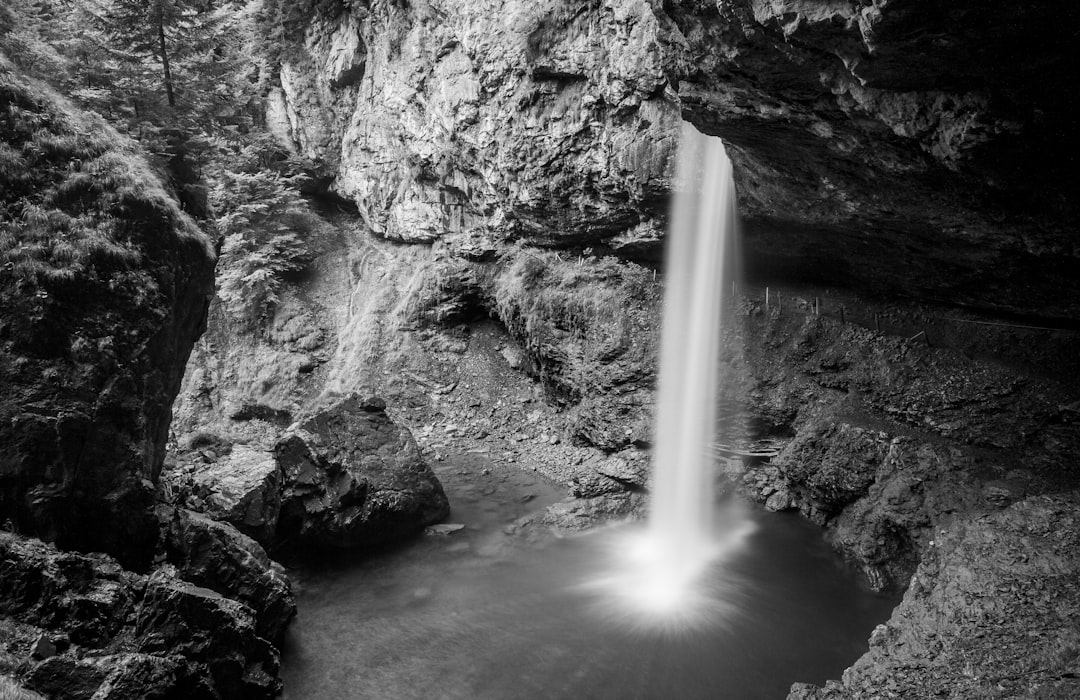 grayscale photo of waterfalls on rocky mountain