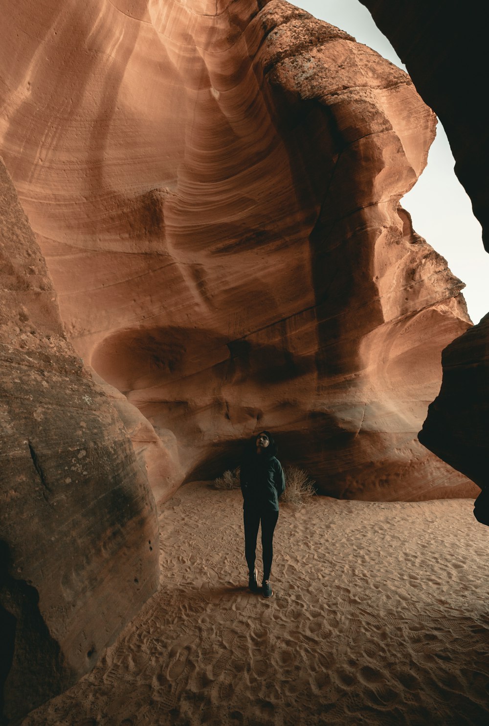 person in black jacket standing on brown rock formation during daytime