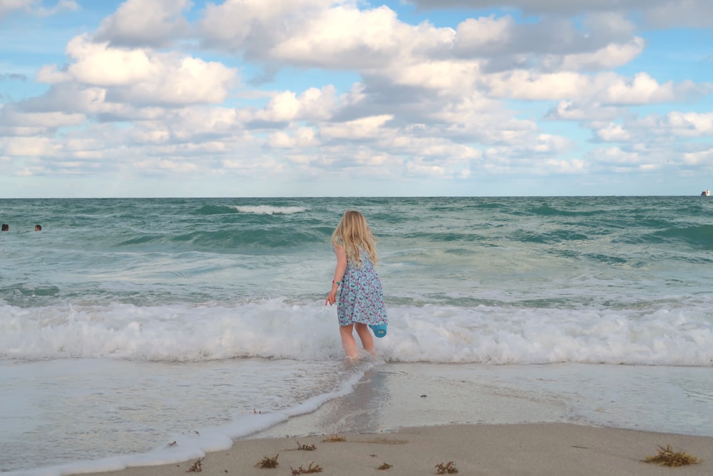 woman in blue and white dress standing on beach during daytime