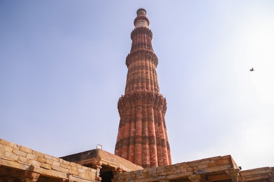 brown concrete tower under blue sky during daytime in क़ुतुब मीनार India