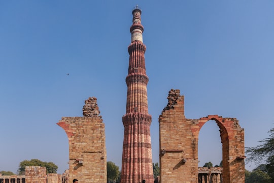 brown brick tower under blue sky during daytime in क़ुतुब मीनार India