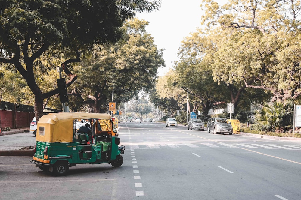 Personas que viajan en rickshaw verde y amarillo en la carretera durante el día
