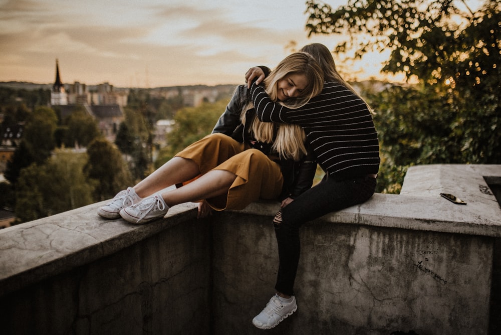 woman in black and white striped long sleeve shirt and brown pants sitting on concrete wall