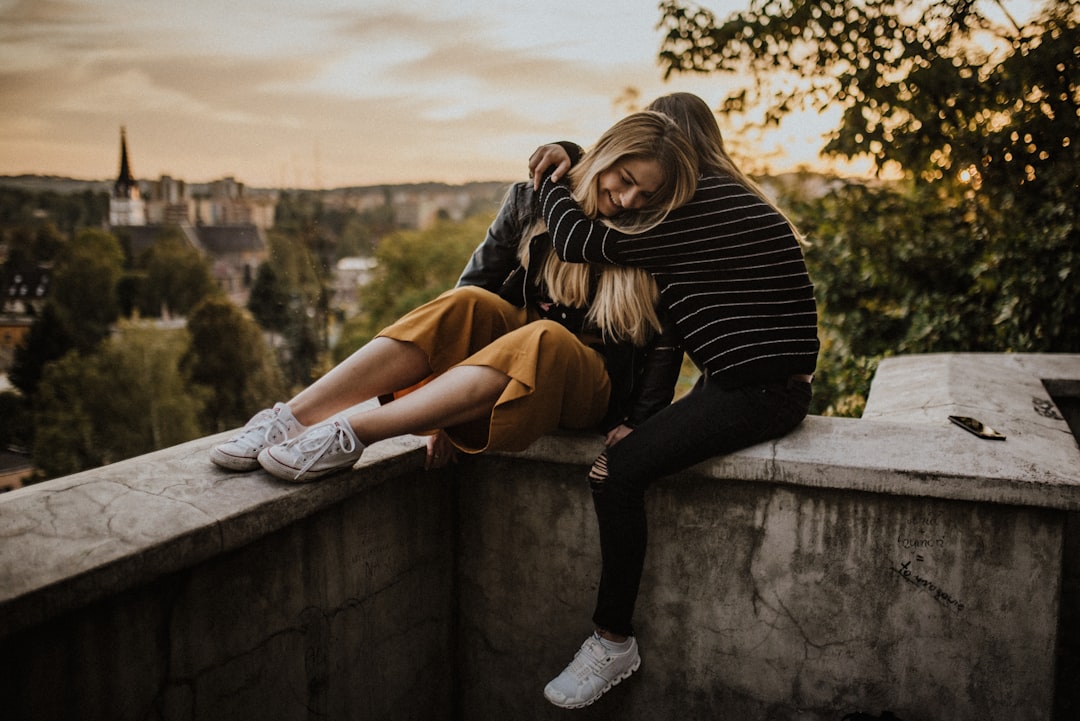 woman in black and white striped long sleeve shirt and brown pants sitting on concrete wall