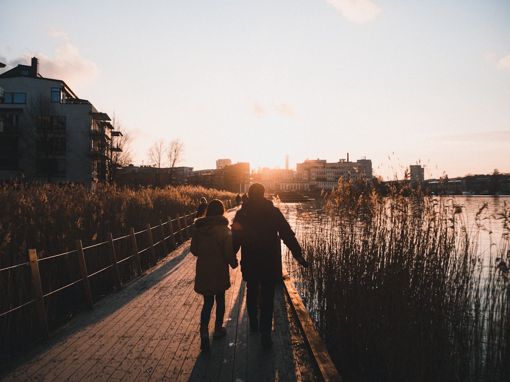 couple walking on wooden bridge during daytime