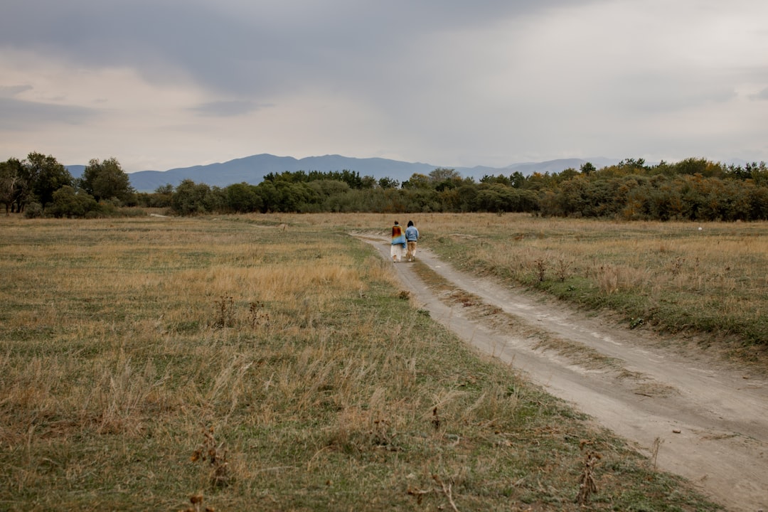 2 people walking on dirt road during daytime