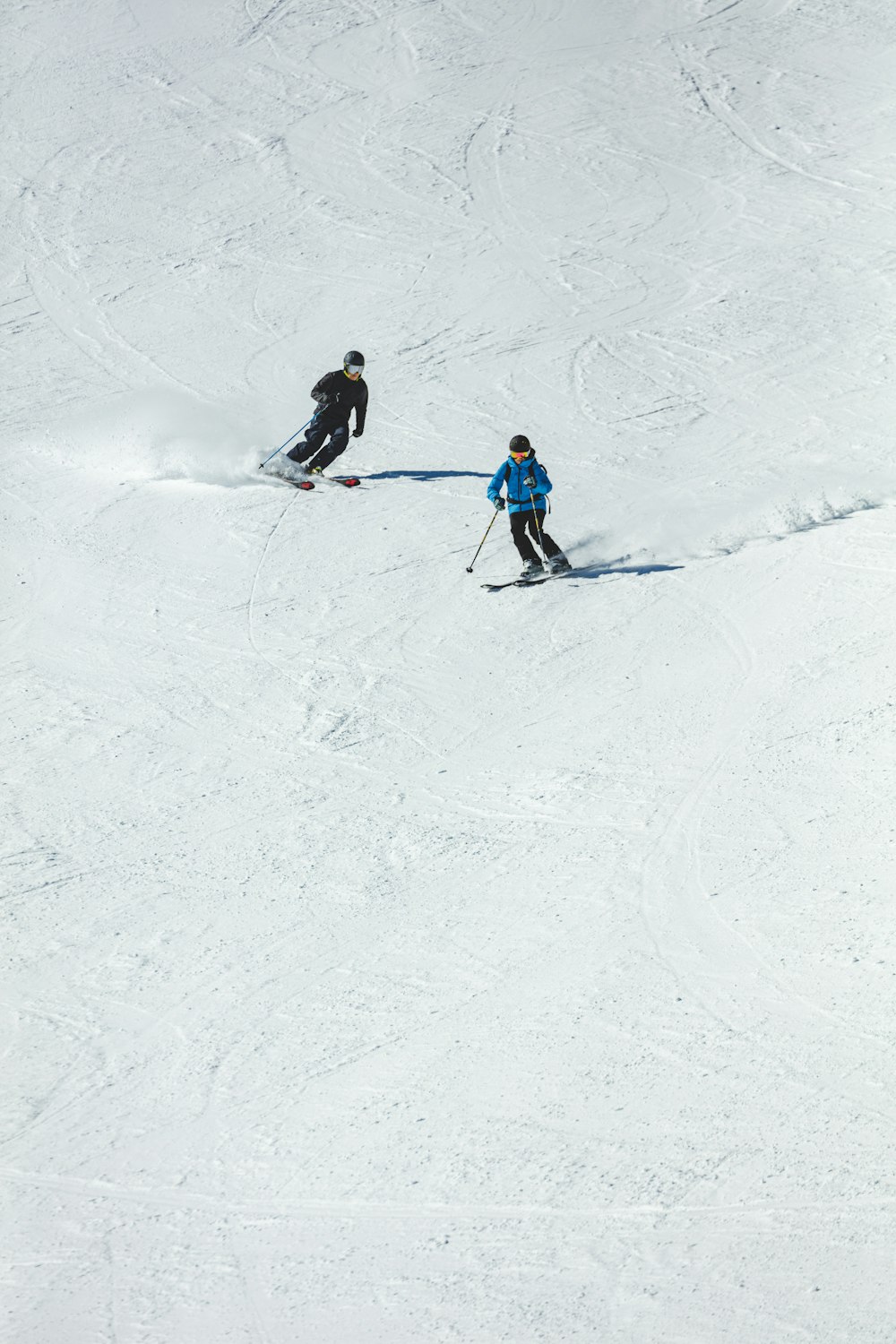 person in blue jacket and black pants riding ski blades on snow covered ground during daytime