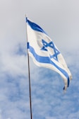 blue and white flag under cloudy sky during daytime
