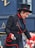 femme en veste de cuir noir et chapeau noir tenant un bâton rouge et blanc