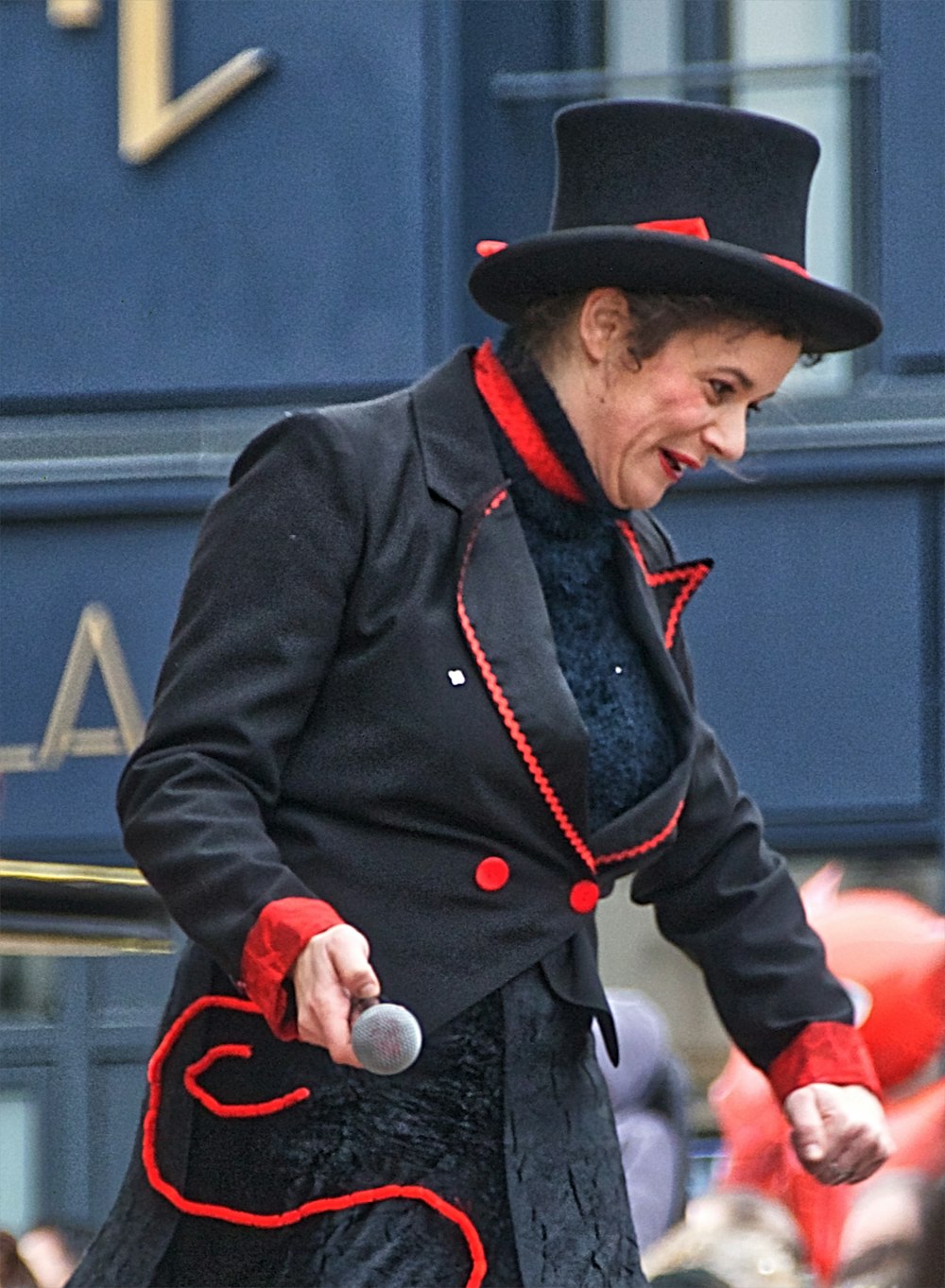 man in black leather jacket and black hat holding red and white stick