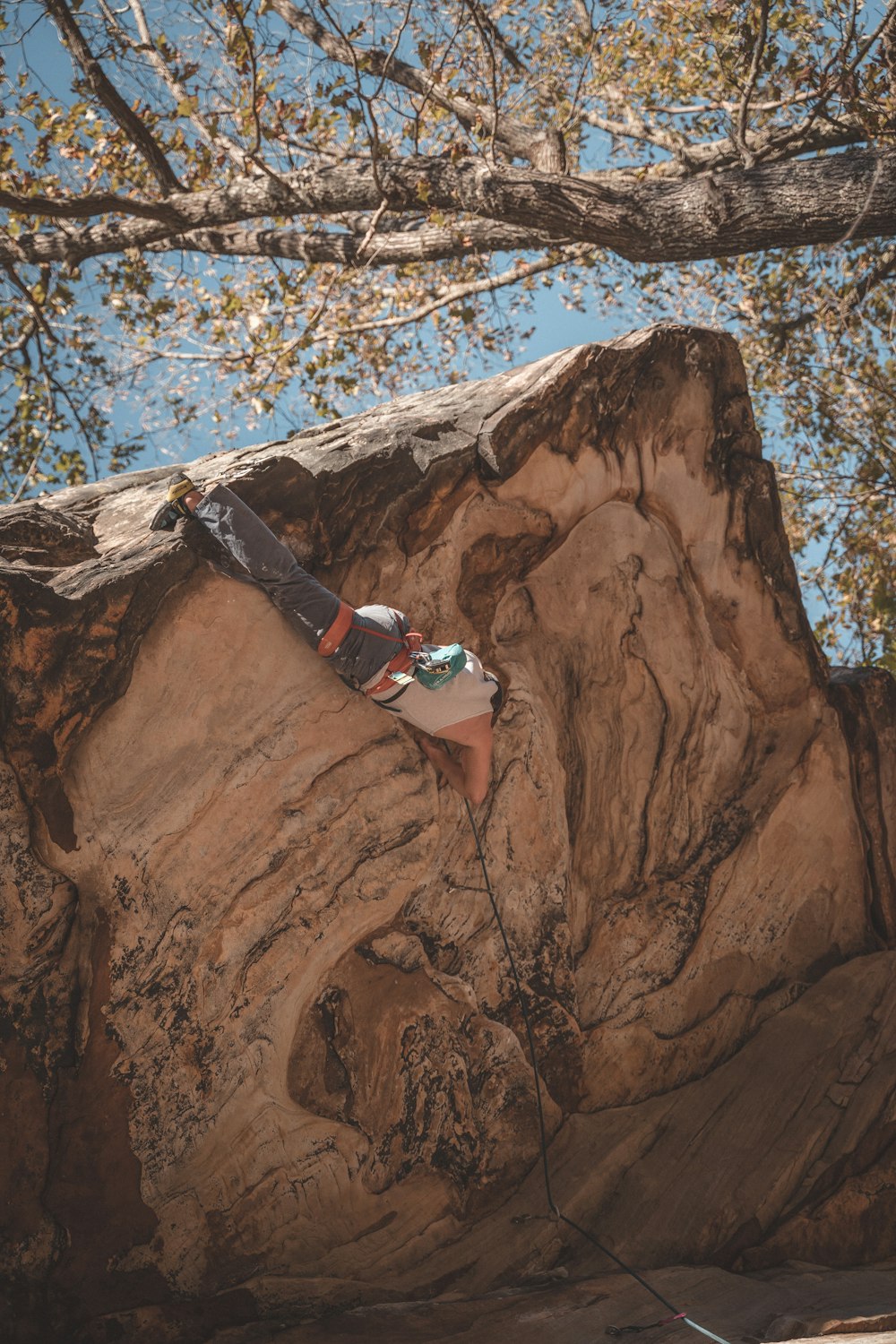 man in blue and white tank top climbing on brown rock formation during daytime