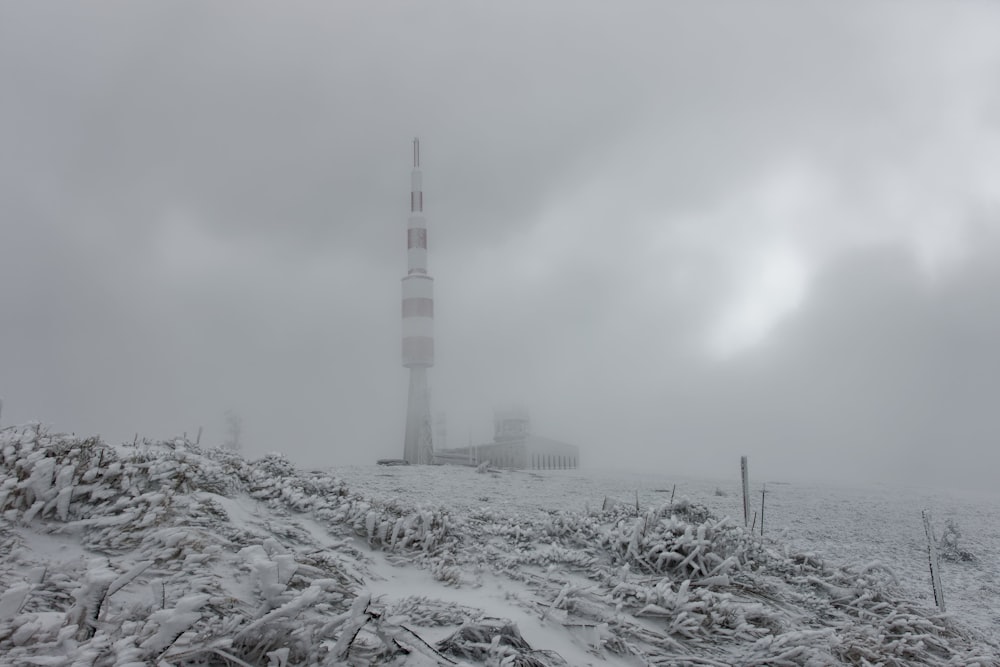 white and red tower surrounded by snow covered field