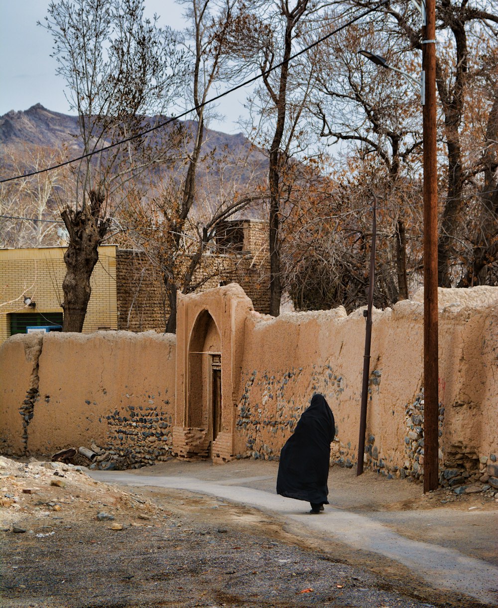 woman in black coat standing near brown concrete building during daytime