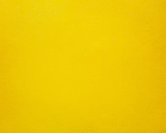 A solid bright yellow wall with a smooth matte texture