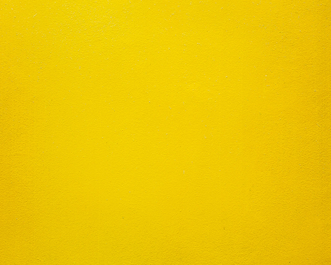 A solid bright yellow wall with a smooth matte texture
