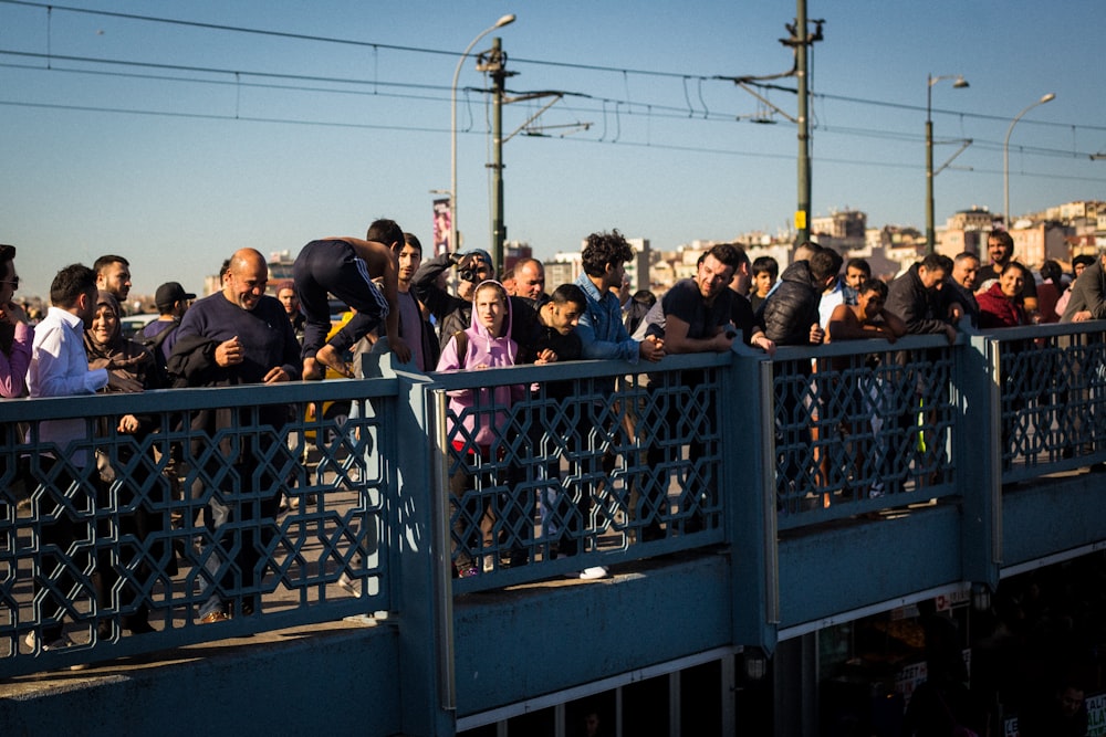 people sitting on black metal fence during daytime