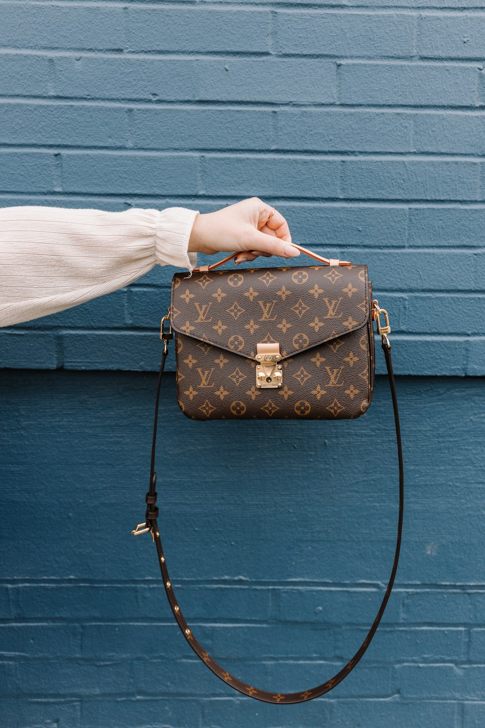 person holding brown leather sling bag