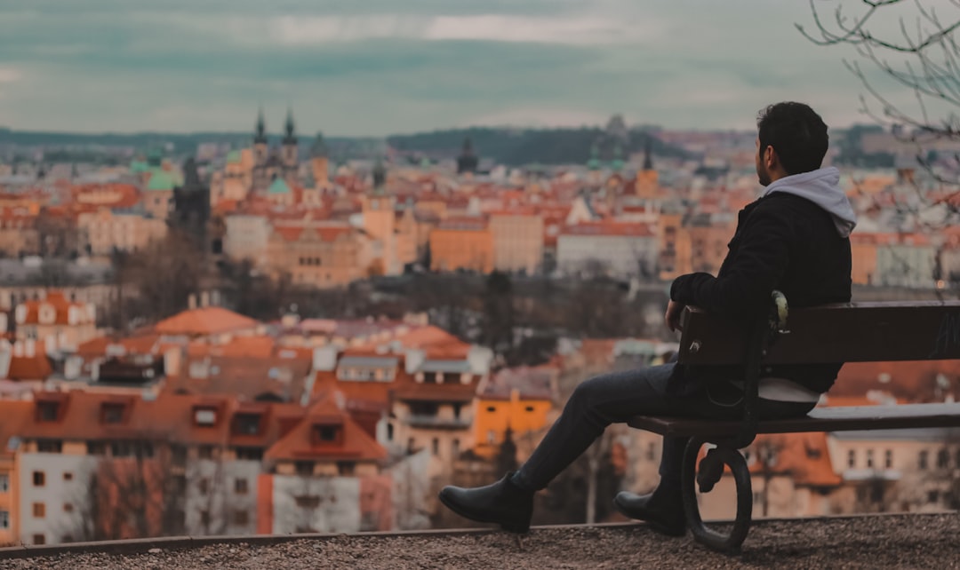 person in black jacket and black pants sitting on brown concrete wall during daytime