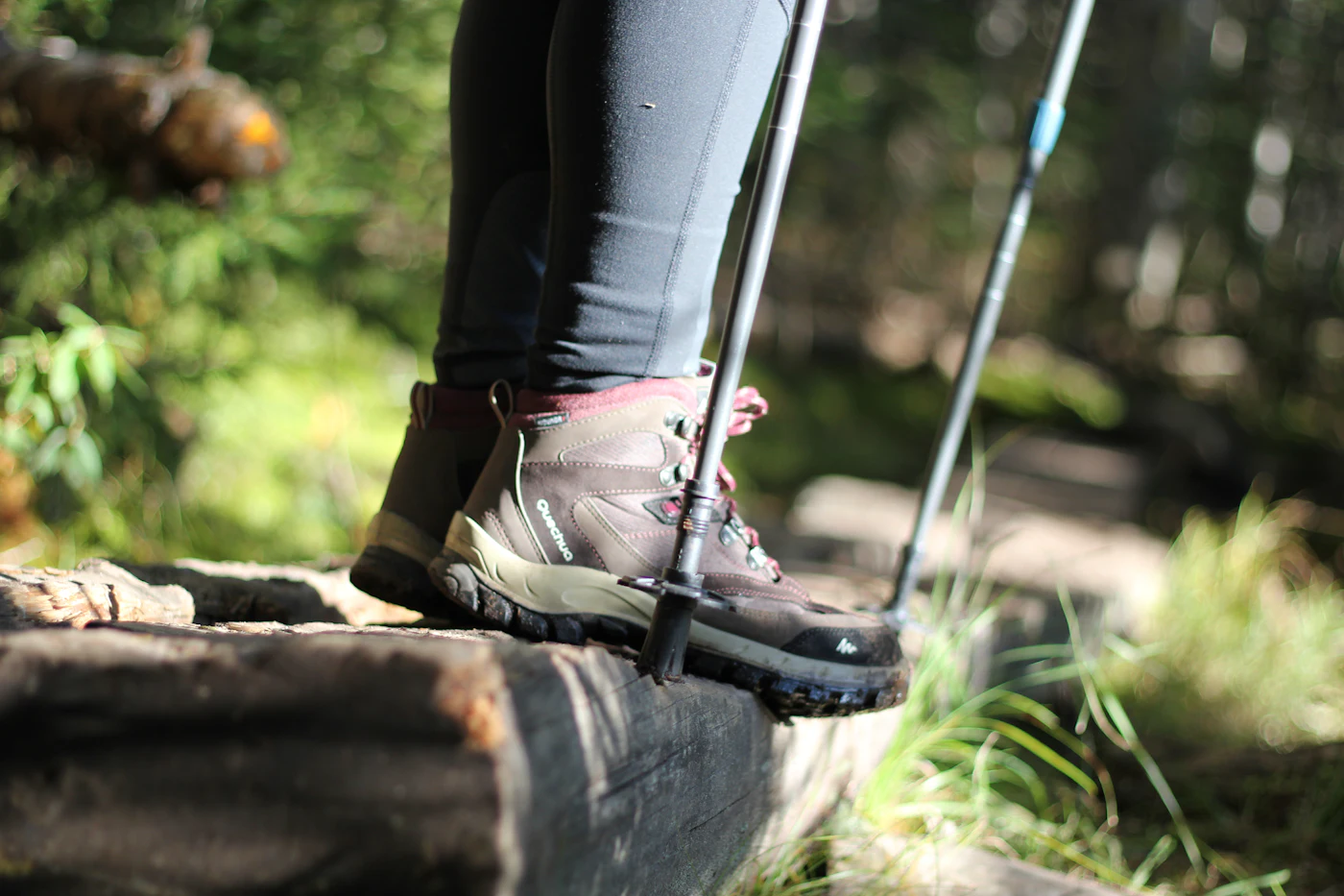 A hiker's boot and trekking pole tip resting on a wooden trail bridge