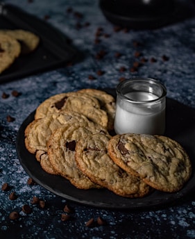 Freshly baked cookies stacked on a rustic plate with a glass of milk