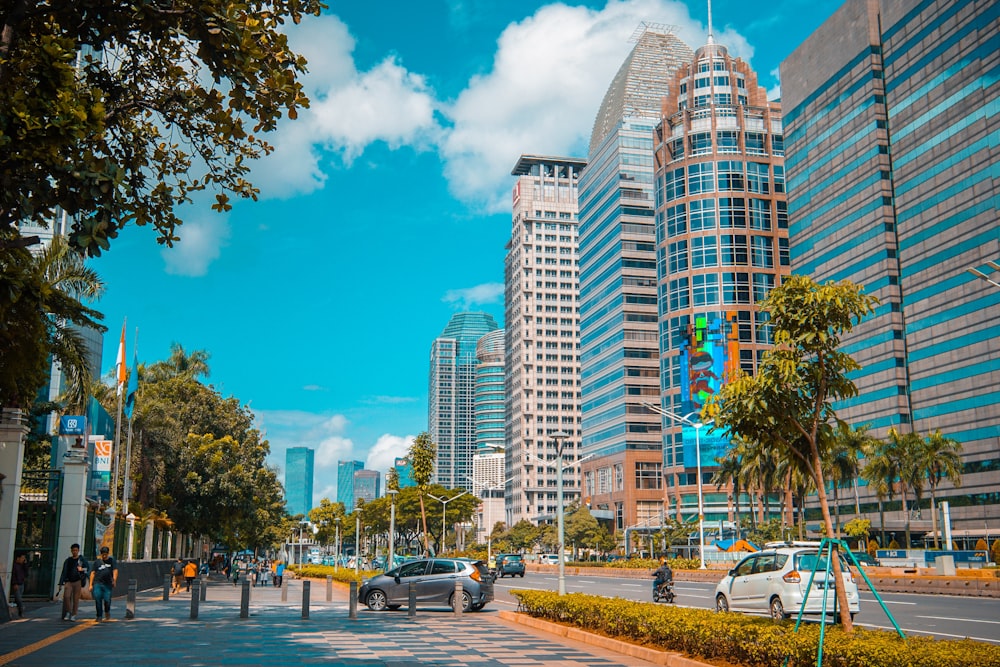 cars parked on side of road near high rise buildings during daytime