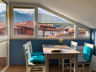 Cozy attic apartment balcony overlooking the lush green mountains and white village rooftops at sunset.