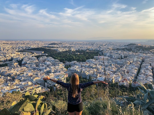 woman in black long sleeve shirt standing on top of the mountain during daytime in Lycabettus hill Greece