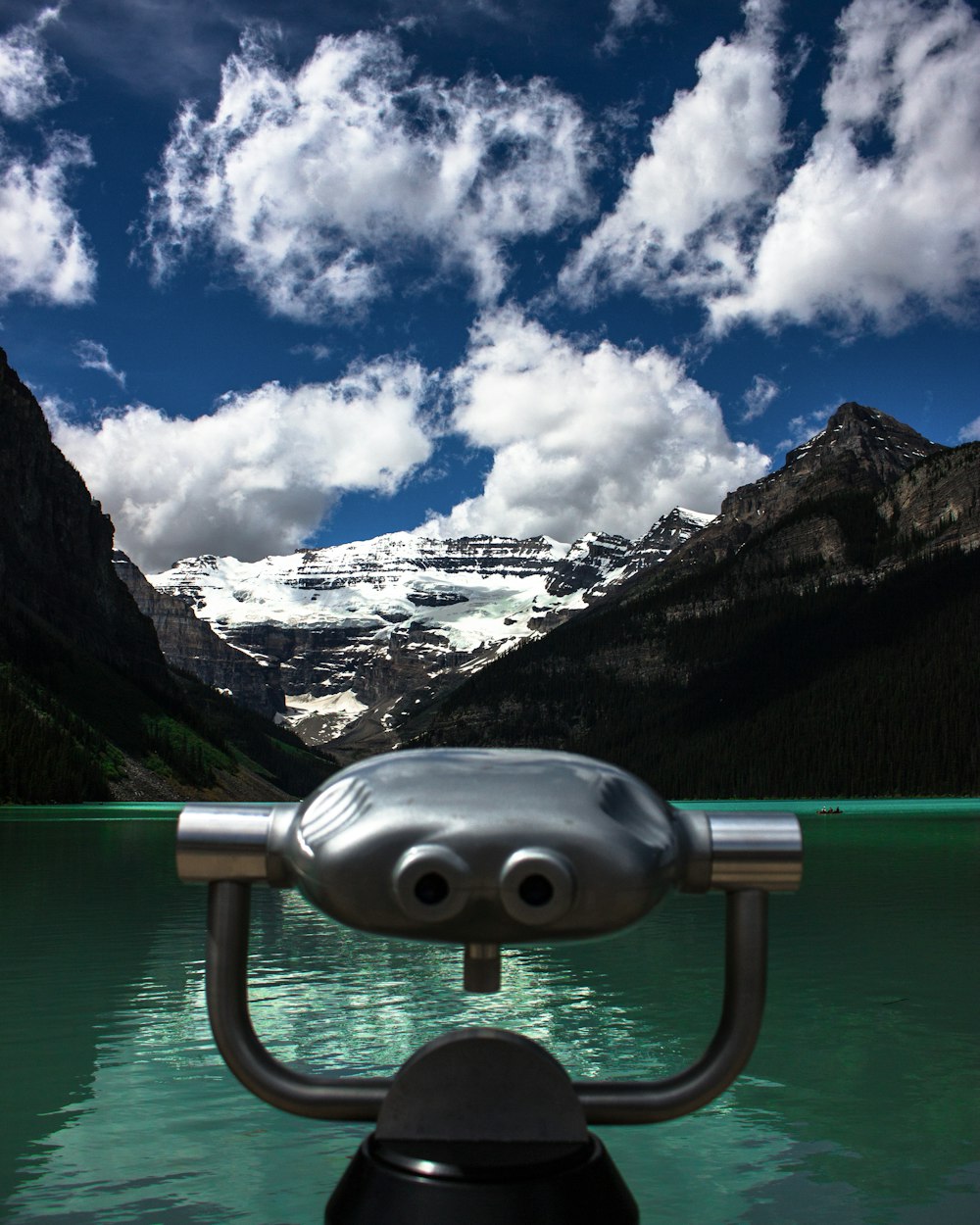 gray coin operated telescope near lake and snow covered mountain during daytime