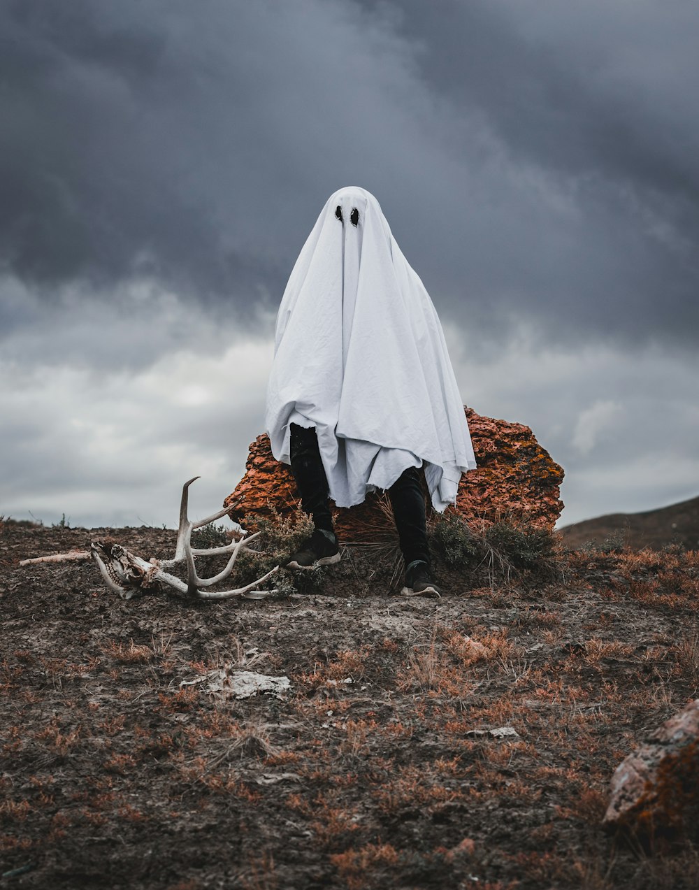 person in white robe standing on brown dried leaves during daytime