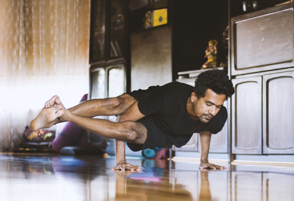 Hombre con camiseta negra y pantalones cortos negros haciendo push up