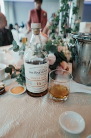 clear glass bottle beside drinking glass on table