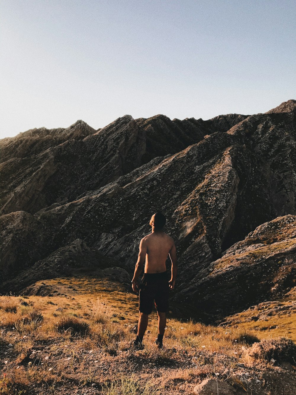 man in black shorts standing on brown grass field during daytime