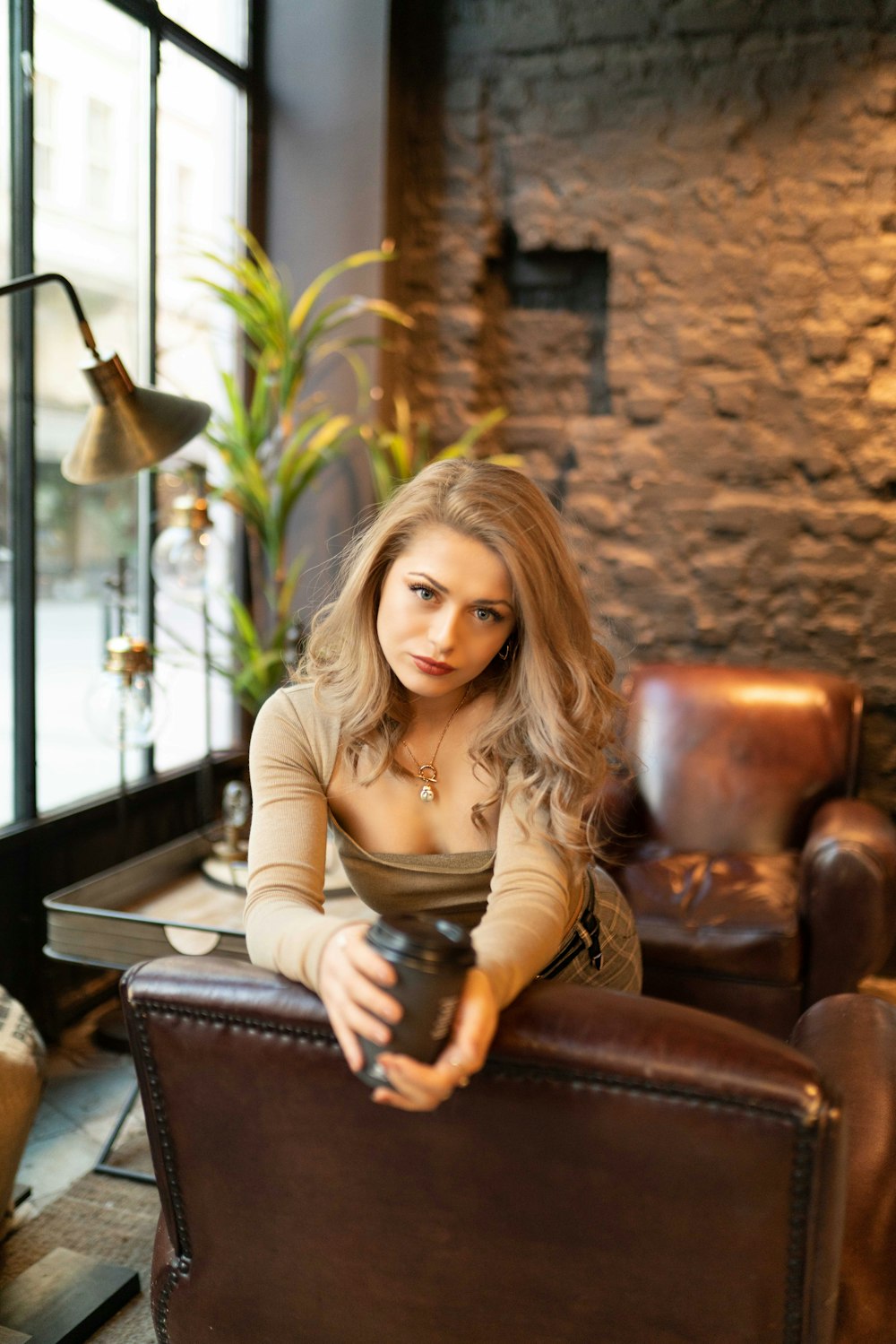 woman in brown long sleeve shirt sitting on brown leather armchair