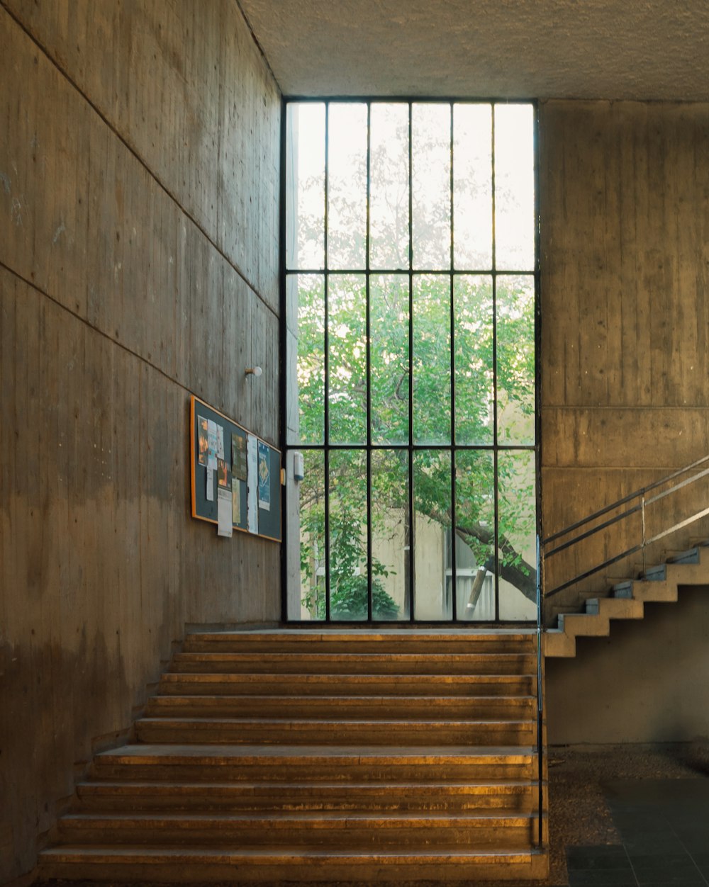 brown concrete staircase near green metal window grill