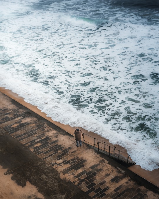 person standing on brown wooden dock near ocean waves during daytime in Saint-Malo France