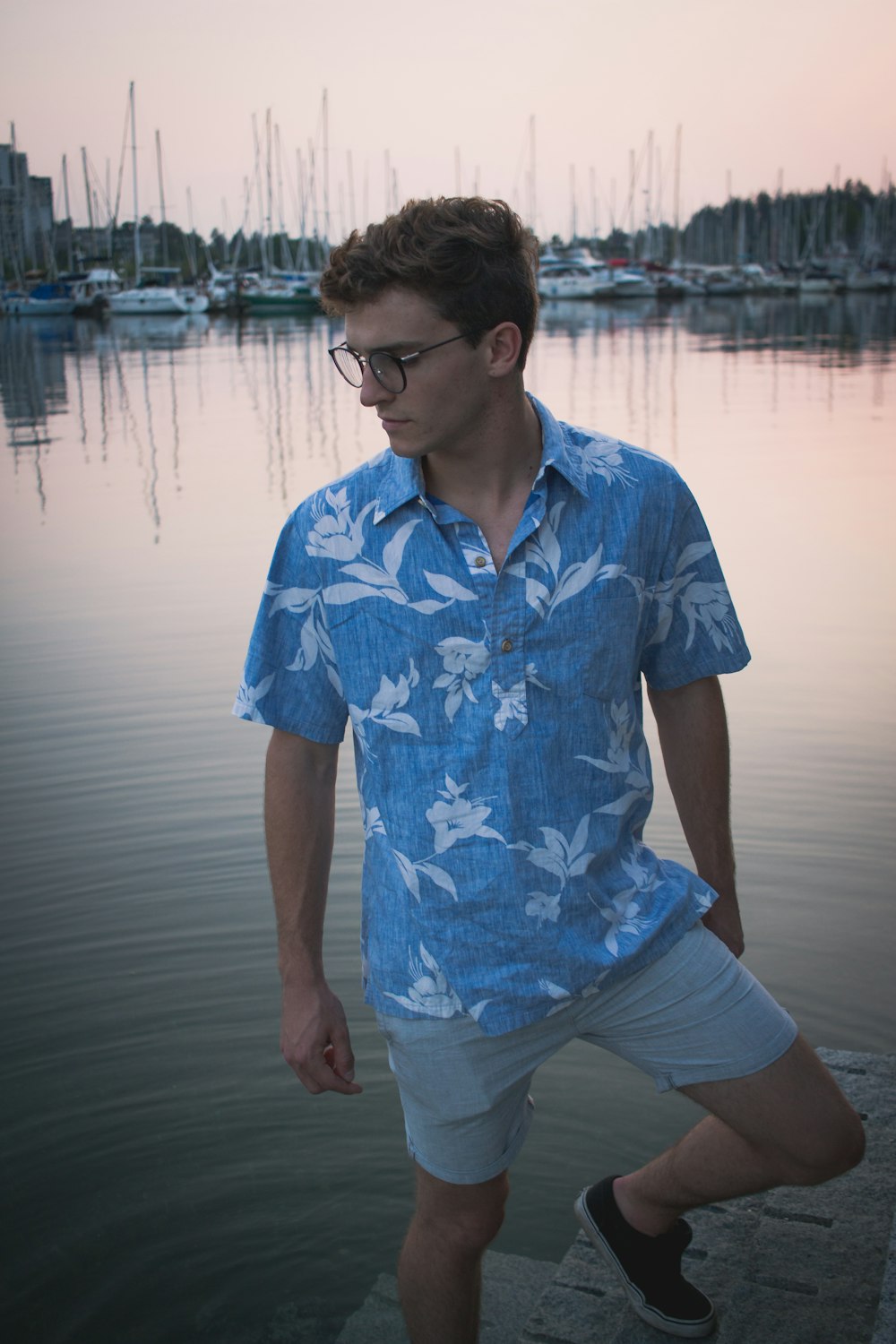 man in blue and white floral button up t-shirt standing near body of water during