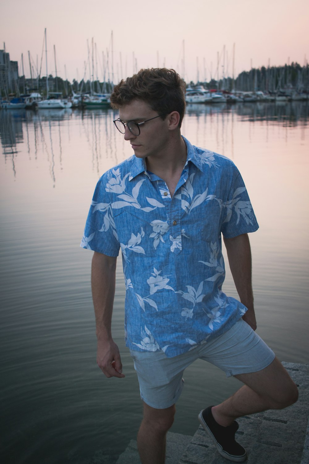 hombre en azul y blanco con botones florales de pie cerca del cuerpo de agua durante