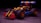 A colorful toy car built from interlocking plastic bricks, featuring large black wheels with red accents. The body of the car includes elements in yellow, red, black, and blue, and it is set against a dark, subtly textured background.