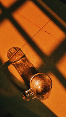 Natural light casting shadows over a simple ceramic cup and saucer.