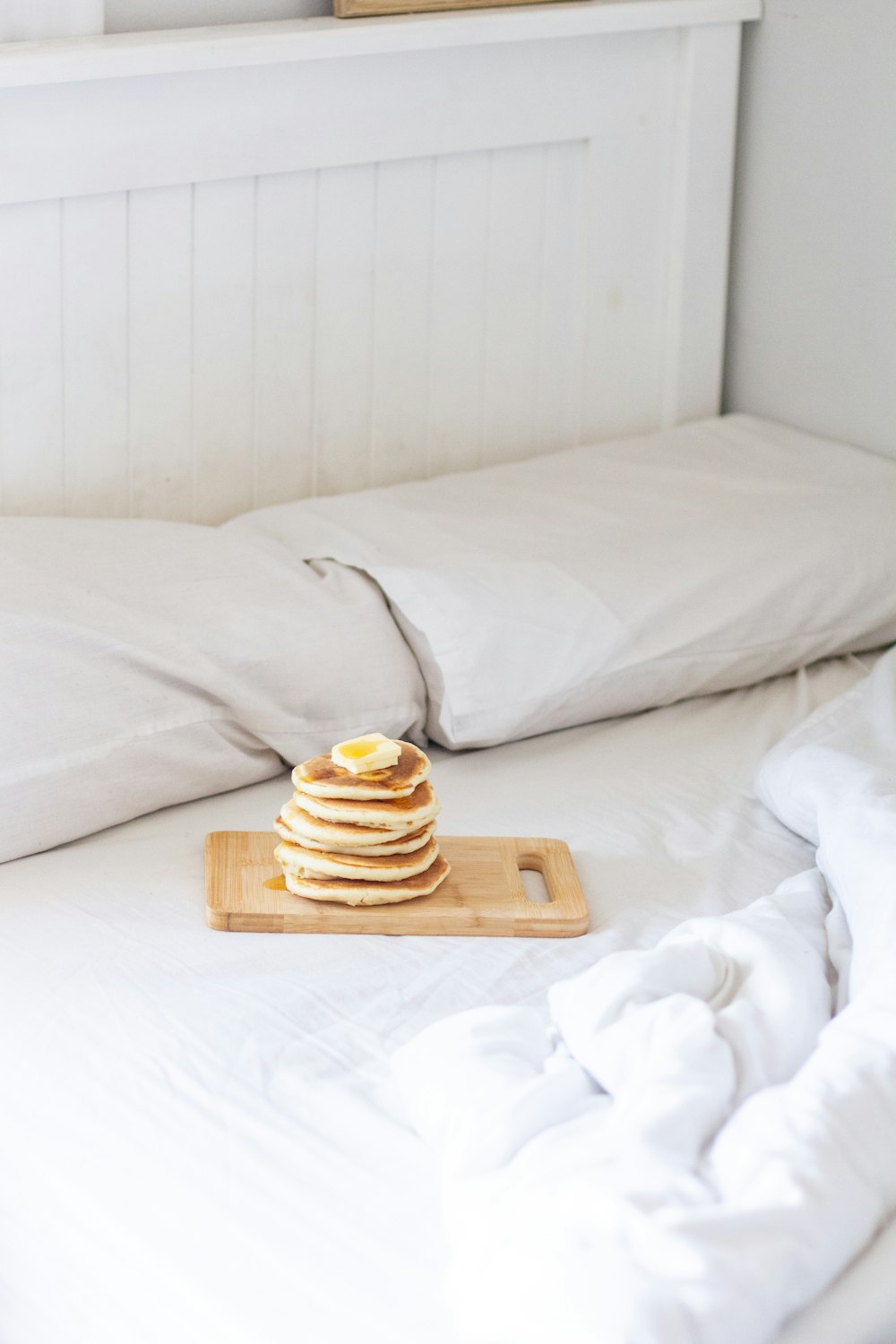 brown and white stripe ceramic mug on brown wooden tray on white bed