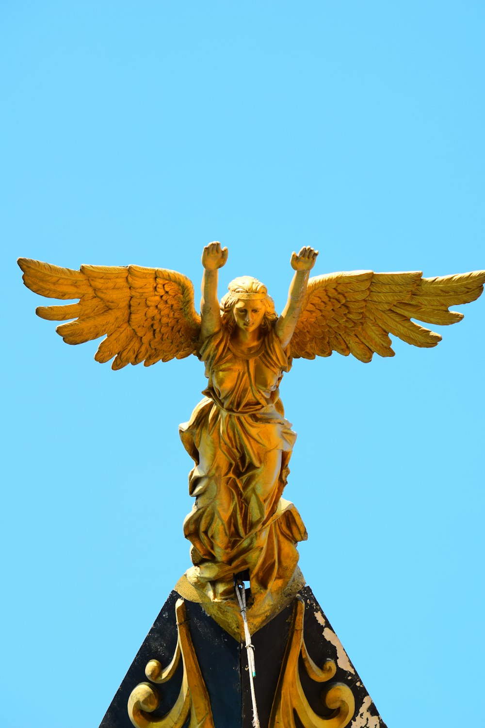 낮 동안 푸른 하늘 아래 금 천사 동상