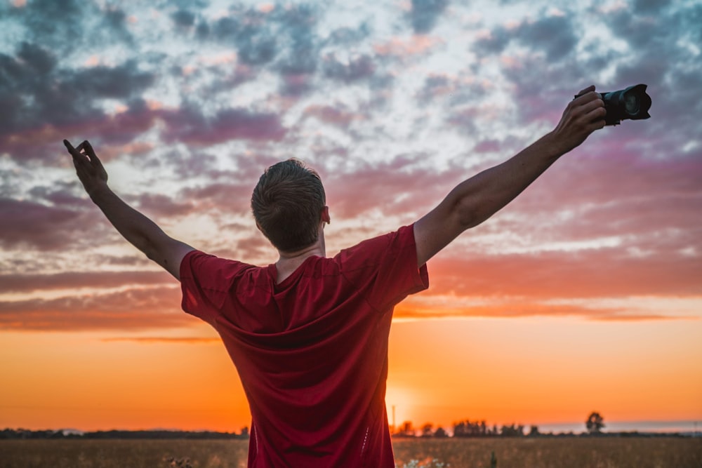 man in red t-shirt raising his hands