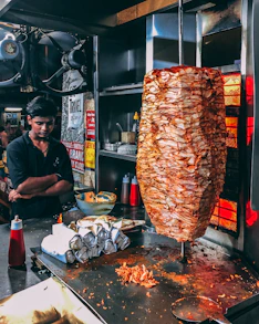 man in black button up shirt standing in front of food display