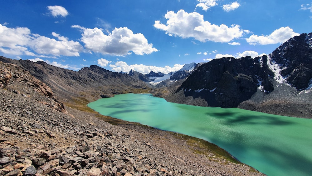 lac au milieu des montagnes sous ciel bleu et nuages blancs pendant la journée