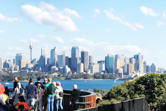 people standing on the edge of a building looking at the city during daytime