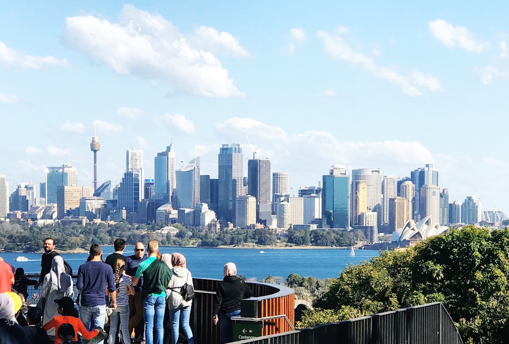 people standing on the edge of a building looking at the city during daytime