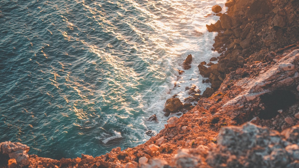 brown rocky shore with blue sea water during daytime