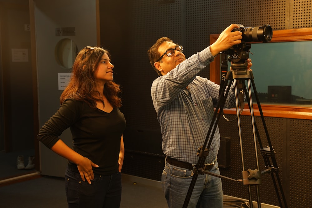 man and woman standing beside black tripod