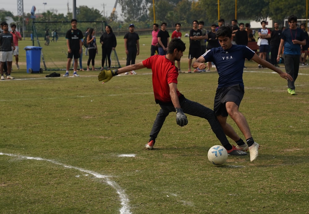 Hombre con camisa roja y pantalones cortos negros jugando al fútbol durante el día